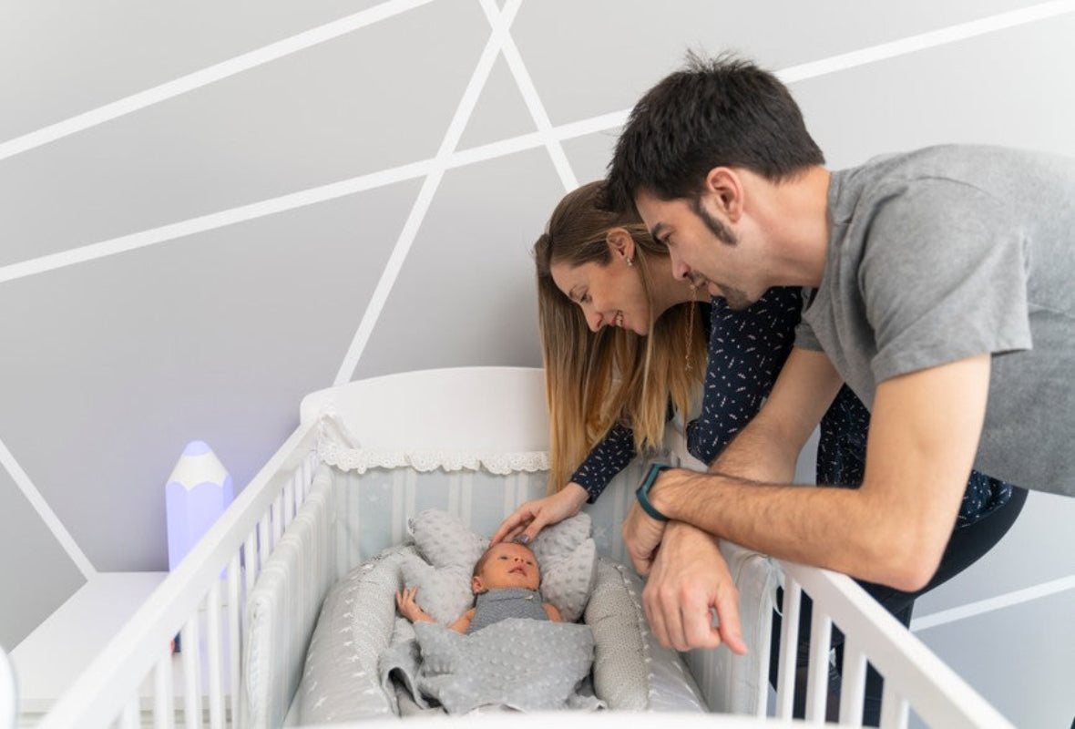 Bébé dans le réducteur de lit dans le berceau, dans la chambre avec papa et maman