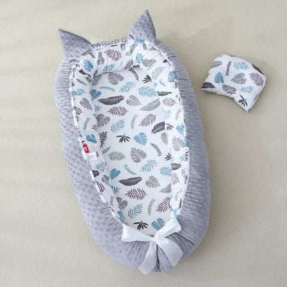Un cocon bébé avec des motifs de feuilles et bordure grise 
