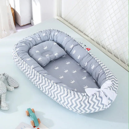 Un cocon pour bébé avec des motifs de couronnes. La couleur est grise.