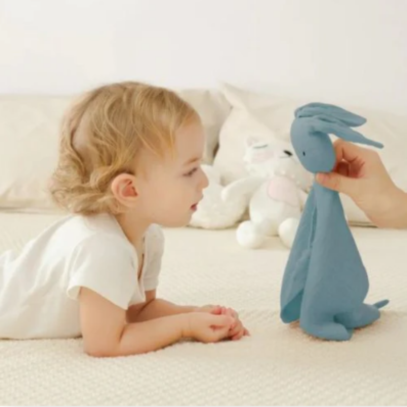 bébé qui joue avec doudou lapin bleu